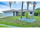 Charming single-story home with a two-car garage, lush green lawn, and mature palm trees at 408 Fletcher St, Port Charlotte, FL 33954