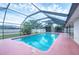 A covered, screened-in outdoor pool surrounded by tropical plants and a pink concrete pad at 408 Fletcher St, Port Charlotte, FL 33954