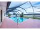 A covered, screened-in outdoor pool with pink concrete, tropical plants, and comfortable access steps at 408 Fletcher St, Port Charlotte, FL 33954