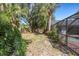 Backyard with tropical landscaping, showcasing the pool cage and brick-paved deck at 4473 Diamond S Cir, Sarasota, FL 34233