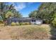 Large backyard with mature landscaping and screened in porch under a blue sky at 4473 Diamond S Cir, Sarasota, FL 34233