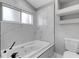 Relaxing bathroom with a sleek tub, white marble-look tile surround, and built-in shelves at 4473 Diamond S Cir, Sarasota, FL 34233