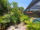 Lush backyard with tropical landscaping, a screened-in pool enclosure, and a serene stone pathway at 4492 Del Sol Blvd, Sarasota, FL 34243