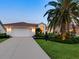 Well-maintained home with a two-car garage, illuminated entrance, mature palm trees, and an expansive driveway, providing ample parking at 4492 Del Sol Blvd, Sarasota, FL 34243