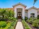 Beautiful front entrance with double doors, white exterior, vibrant landscaping, and a red tile roof, creating a warm welcome at 4492 Del Sol Blvd, Sarasota, FL 34243