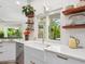 Bright kitchen featuring a farmhouse sink, stainless steel dishwasher, and floating shelves at 4492 Del Sol Blvd, Sarasota, FL 34243