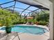Screened-in pool area with lounge chairs and an umbrella, surrounded by lush landscaping and clear blue skies at 4492 Del Sol Blvd, Sarasota, FL 34243