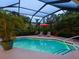Scenic pool area with a screened lanai, lush greenery, and comfortable lounge chairs for relaxation and enjoyment at 4492 Del Sol Blvd, Sarasota, FL 34243