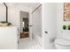 Clean bathroom with white tile, a toilet, and a view into another room with wood flooring at 4506 17Th W St, Palmetto, FL 34221