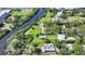 Aerial view of a waterfront property with a pool, lush landscaping, and proximity to a school at 4771 Riverwood Cir, Sarasota, FL 34231