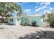 Home's backyard with white gravel, patio set, grill, and a view of the turquoise home exterior and foliage at 5026 Calle Minorga, Sarasota, FL 34242