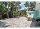 Spacious backyard with light gravel, outdoor furniture, grill, partial landscaping, and the turquoise exterior of the house at 5026 Calle Minorga, Sarasota, FL 34242