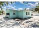 Exterior angle of turquoise single-story house featuring window views, an air conditioning unit, and light gravel surroundings at 5026 Calle Minorga, Sarasota, FL 34242