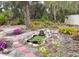 Lush backyard garden featuring colorful flowers, a pond, and mature trees at 5353 Shadow Lawn Dr, Sarasota, FL 34242