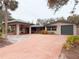 Single-story home with brick driveway and carport, surrounded by lush greenery at 5353 Shadow Lawn Dr, Sarasota, FL 34242