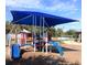 Colorful playground with slides and swings, shaded by a blue awning for sun protection at 5353 Shadow Lawn Dr, Sarasota, FL 34242