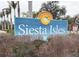 Community sign for Siesta Isles with palm trees in the background at 5353 Shadow Lawn Dr, Sarasota, FL 34242