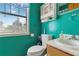 Bright turquoise bathroom featuring a toilet, sink, vanity and white-framed window at 5403 Fleming St, Port Charlotte, FL 33981