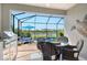 The screened-in lanai features a table setting, outdoor kitchen, and a serene view of the pool and lake at 5475 Summit Gln, Bradenton, FL 34203