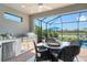 A screened-in lanai with a stainless grill, outdoor kitchen, and a view of the lake and pool at 5475 Summit Gln, Bradenton, FL 34203