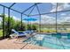 Relax in this screened-in pool and spa with a lake view, surrounded by lush landscaping and lounge chairs at 5475 Summit Gln, Bradenton, FL 34203