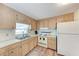 The kitchen has matching wood cabinets, wood flooring, and is equipped with a white refrigerator and stove at 5619 Bayshore Rd # 203, Palmetto, FL 34221