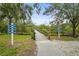 Wooden bridge leading to community amenities with distance signage under a canopy of lush trees and blue skies at 5646 Simonton St, Bradenton, FL 34203