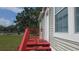 Exterior home view with a red painted wood porch, stairs and railing leading to the front door at 6238 Angus Valley Dr, Wesley Chapel, FL 33544