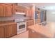 Well-lit kitchen featuring wood cabinetry, white appliances, and a functional island with a built-in sink at 6238 Angus Valley Dr, Wesley Chapel, FL 33544