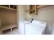Functional laundry area includes washer, dryer, storage cabinets and bench with seat at 6238 Angus Valley Dr, Wesley Chapel, FL 33544