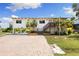 Inviting waterfront home with a well-maintained exterior, brick driveway, and lush tropical landscaping at 6406 Lincoln Rd, Bradenton, FL 34203
