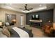 Modern main bedroom with fireplace, TV, wood floors, ceiling fan, and large format mirror at 6713 Taneytown St, North Port, FL 34291