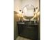 Stylish powder room with a round mirror, decorative lighting, a stone countertop, and modern fixtures at 6713 Taneytown St, North Port, FL 34291