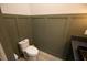 Modern powder room featuring stylish green wall panels, a toilet, and a granite vanity with a dark sink at 6713 Taneytown St, North Port, FL 34291