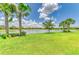 Manicured backyard overlooking a lake lined with palm trees with blue skies and white clouds at 6756 Chester Trl, Lakewood Ranch, FL 34202