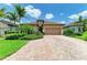 Charming single-story home featuring lush landscaping, a brick driveway, and a two-car garage at 6756 Chester Trl, Lakewood Ranch, FL 34202