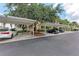 Parking area with covered parking spaces and mature trees providing shade at 7911 Grand Estuary Trl # 102, Bradenton, FL 34212
