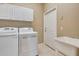 Bright laundry room with white washer, dryer, sink, and storage cabinets at 8047 Desoto Woods Dr, Sarasota, FL 34243