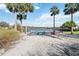Sandy lakeside beach with colorful Adirondack chairs under palm trees creating a relaxing waterfront oasis at 8224 Simpson Falls Ct # 8224, Sarasota, FL 34243