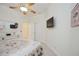 Bright bedroom with carpet, ceiling fan, TV, white dresser, closet, and an entry door at 8224 Simpson Falls Ct # 8224, Sarasota, FL 34243