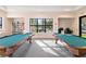 Billiard room with two pool tables, a bookcase, and large windows for natural light at 8224 Simpson Falls Ct # 8224, Sarasota, FL 34243