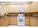 Bright kitchen featuring granite counters, light wood cabinets, and white appliances at 8224 Simpson Falls Ct # 8224, Sarasota, FL 34243