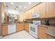 Open kitchen with granite countertops, light wood cabinets, and a view into the dining and living areas at 8224 Simpson Falls Ct # 8224, Sarasota, FL 34243