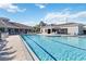 Large, bright swimming pool surrounded by lounge chairs and palm trees with adjacent buildings at 8224 Simpson Falls Ct # 8224, Sarasota, FL 34243
