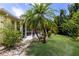 This home features a lush green backyard with a beautiful palm tree and screened-in porch at 915 Sw Barclay Ct, Venice, FL 34293