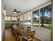 Bright sunroom with large windows, ceiling fan and a long dining table with seating for ten at 915 Sw Barclay Ct, Venice, FL 34293