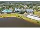 Aerial view of lakefront clubhouse featuring pool, beach, beach volleyball, and lush landscaping at 11194 Spring Point Cir, Riverview, FL 33579