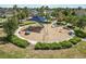 Community playground featuring shaded play structures, surrounded by lush landscaping and pathways at 11194 Spring Point Cir, Riverview, FL 33579