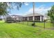 Spacious backyard with a black metal fence, grassy lawn, lush landscaping, and a screened-in pool area at 1015 143Rd Ne St, Bradenton, FL 34212