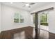 Bedroom features dark hardwood floors, a modern ceiling fan, and sliding glass doors to the screened patio at 1015 143Rd Ne St, Bradenton, FL 34212